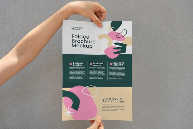 Kobiece ręce trzymające makiety trójdzielnej broszury o abstrakcyjnych kształtach