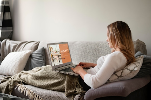 Kobieta pracująca w domu przy laptopie na kanapie