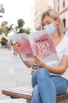 Kobieta z maską na ulicy czytania książki