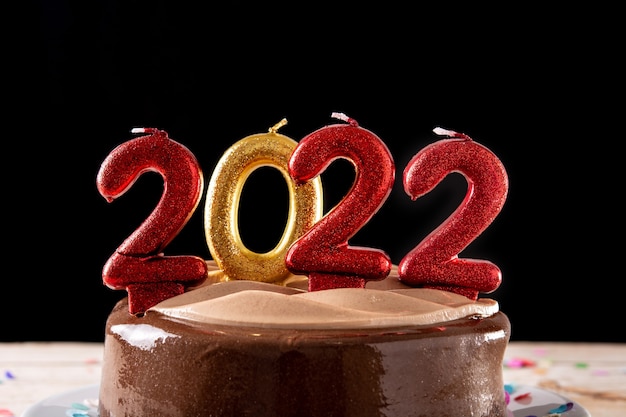 Bezpłatne zdjęcie 2022 tort i ozdoby na drewnianym stole i czarnym tle