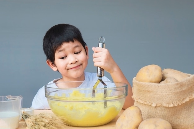 7 lat chłopiec szczęśliwie robi puree ziemniaczane