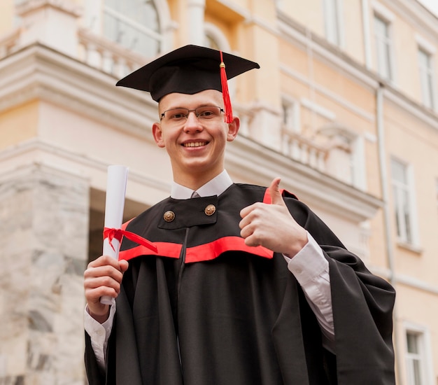 Absolwent chłopiec pokazuje ok znaka