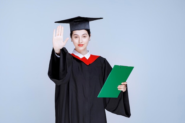 Absolwent z dyplomem wskazujący znak stop. Zdjęcie wysokiej jakości