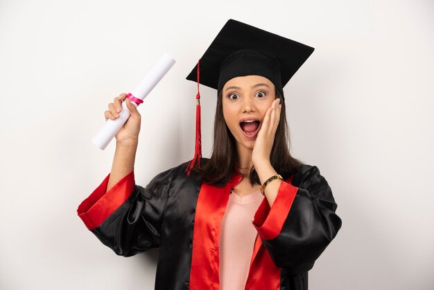 Absolwentka college'u w sukni czuje się szczęśliwa na białym tle.