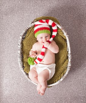 Adorable baby w boże narodzenie kapelusz gnome leżące w koszu. fotografia noworodkowa