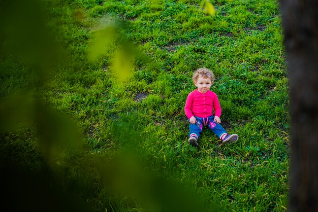 Adorable Mały Chłopiec siedzi na trawniku