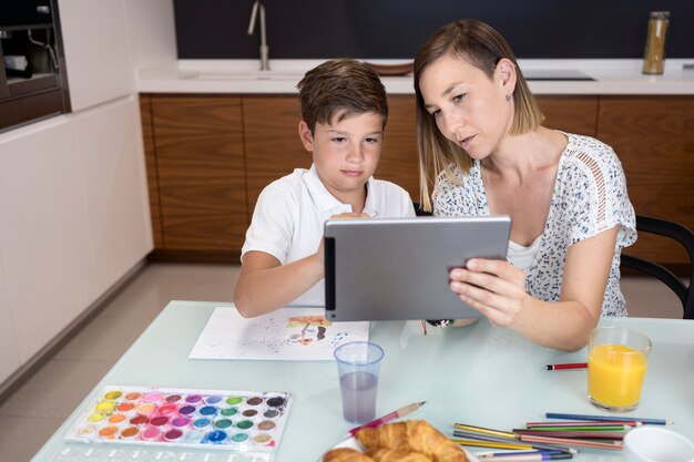 Adorable młody chłopak sprawdza tablet z matką