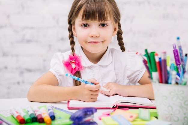 Adorable uczennica uśmiecha aparatu fotograficznego