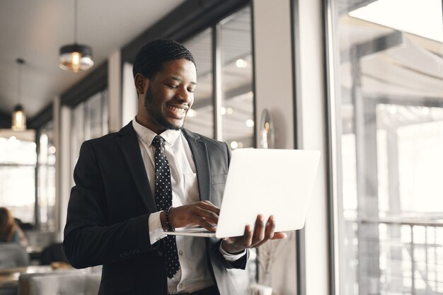 African American biznesmen za pomocą laptopa w kawiarni.