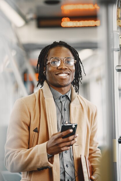 African American człowiek jedzie w autobusie miejskim. Facet w brązowym płaszczu.