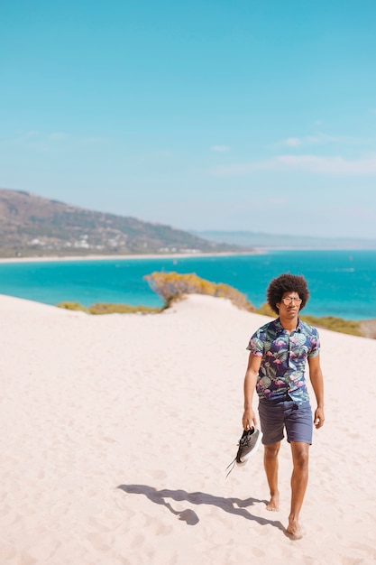 African American mężczyzna chodzenie boso po plaży