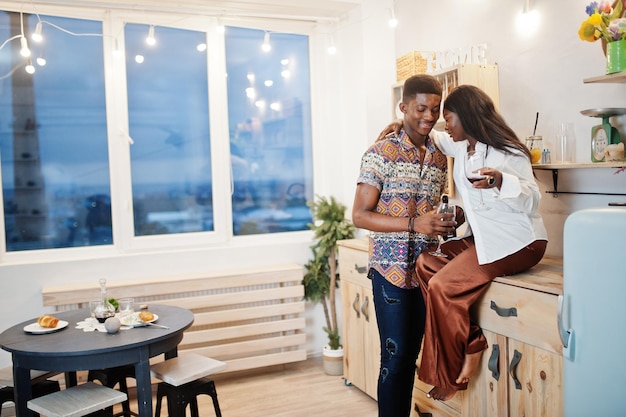 Afro-amerykańska para zakochanych pije wino w kuchni na romantycznej randce