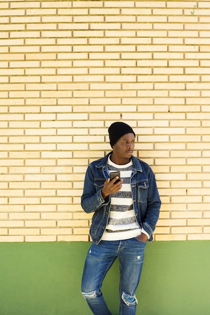 Afro amerykański mężczyzna z smartphone przed ścianą