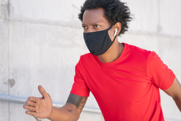 Bezpłatne zdjęcie afro lekkoatletycznego mężczyzna nosi maskę i działa na zewnątrz. nowy normalny styl życia. koncepcja sportu i zdrowego stylu życia.
