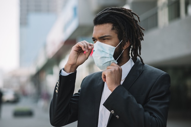 Bezpłatne zdjęcie afroamerican mężczyzna naprawia medyczną maskę