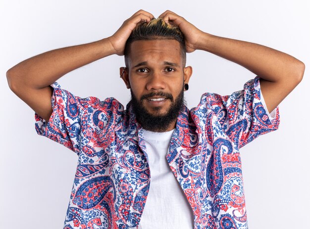 Afroamerykanin Młody Człowiek W Kolorowej Koszuli Patrzący Na Kamerę Mylony Z Rękami Na Głowie