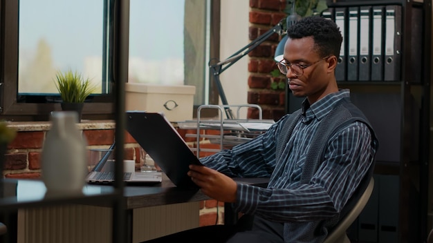 Afroamerykanin pracownik analizujący raport zakupów e na laptopie w miejscu pracy. konsultant biznesowy planujący statystyki finansowe w celu rozwoju komercyjnego i wzrostu firmy.