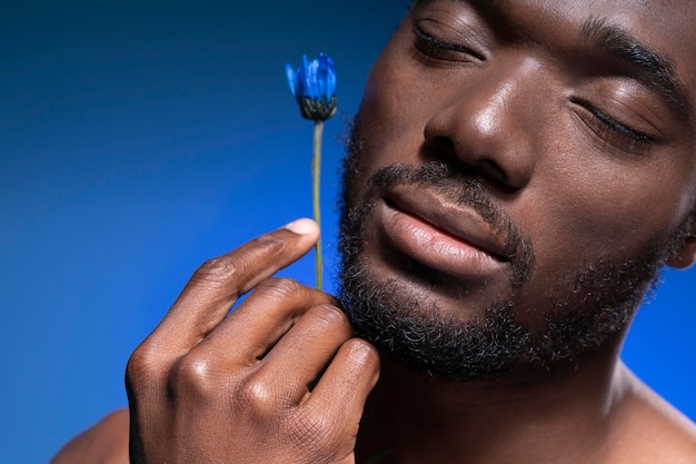Bezpłatne zdjęcie afroamerykanin trzyma niebieski kwiat