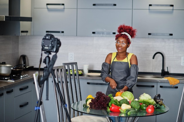 Afroamerykanka filmuje na swoim blogu audycję o zdrowej żywności w domowej kuchni. Kroi pomidora nożem