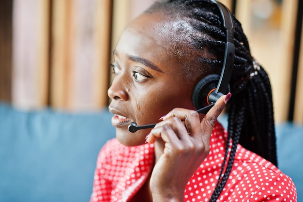 Afroamerykanka pracuje w call center operatora i agenta obsługi klienta, nosząc słuchawki z mikrofonem, pracując na laptopie
