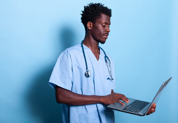 Afroamerykański asystent medyczny patrzący na laptopa w ręku