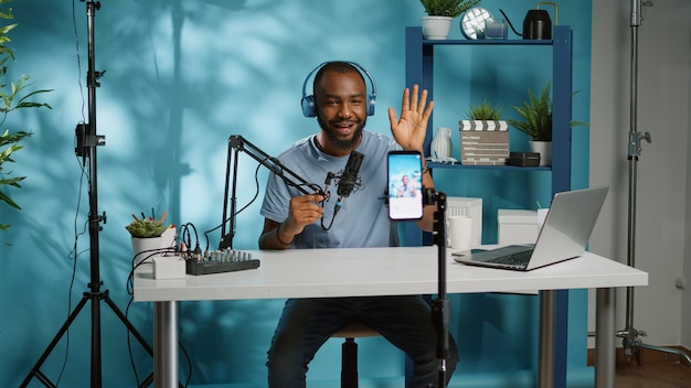 Afroamerykański vloger używający smartfona do kręcenia podcastu