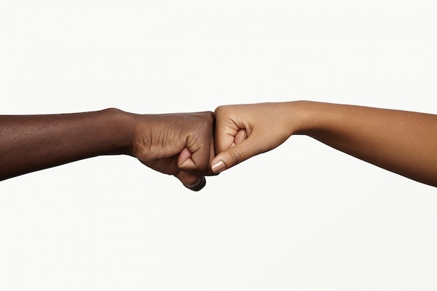 Afrykanin dotykający kostek ciemnoskórą kobietą na znak porozumienia, partnerstwa i współpracy.