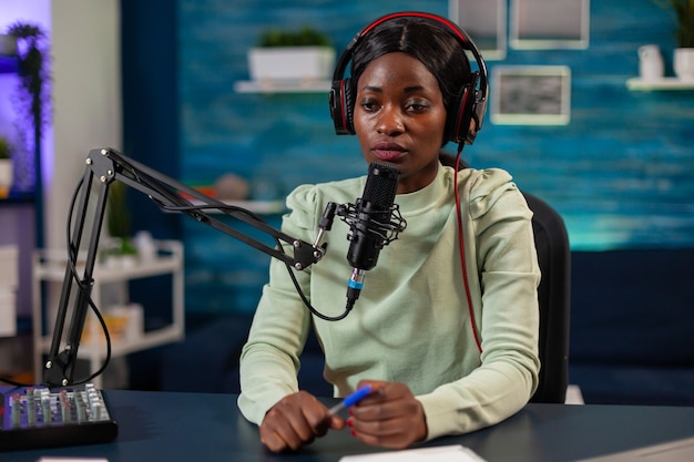 Afrykańska Kobieta Prowadząca Program Online Rozmawiająca Do Mikrofonu W Słuchawkach. Przemawiając Podczas Transmisji Na żywo, Bloger Dyskutujący W Podkaście W Słuchawkach.