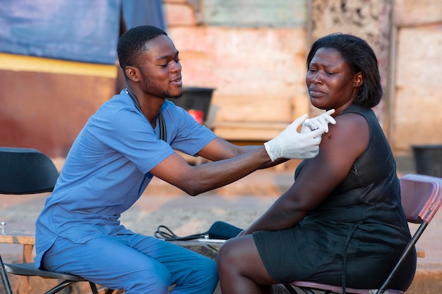 Bezpłatne zdjęcie afrykański lekarz pomocy humanitarnej opiekujący się pacjentem
