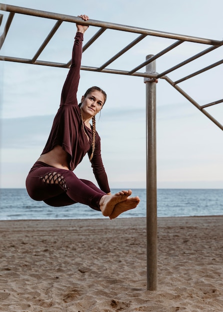 Bezpłatne zdjęcie aktywna kobieta robi ćwiczenia fitness na świeżym powietrzu przy plaży