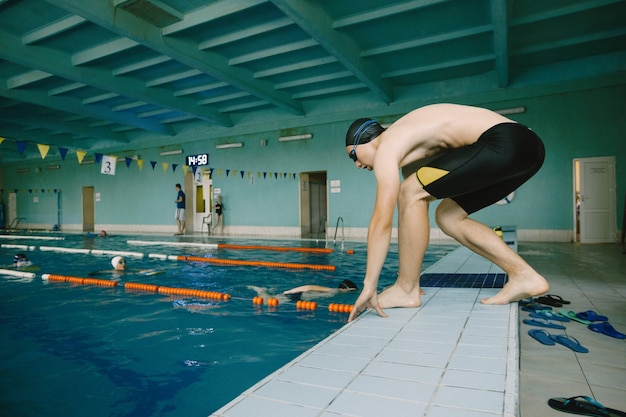 Aktywny pływak skaczący w basenie, start w zawodach. Kryty basen. Europejski.