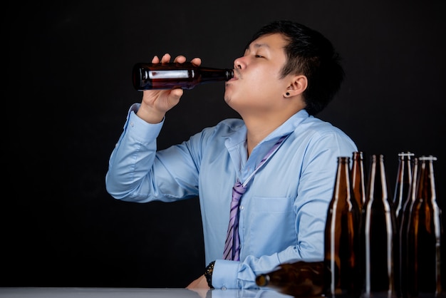 Alkoholik azjatycki człowiek z dużą ilością butelek piwa