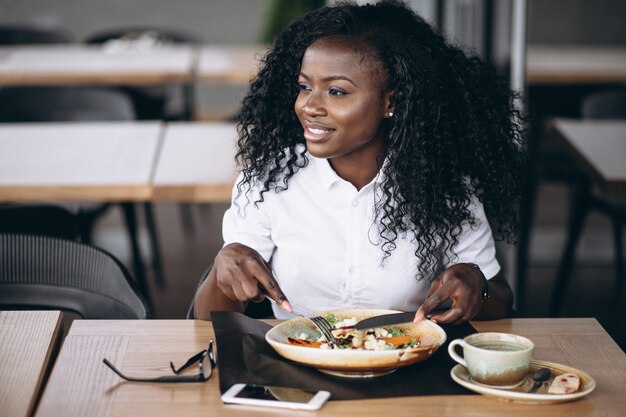 Amerykanin afrykańskiego pochodzenia biznesowej kobiety łasowania sałatka w kawiarni