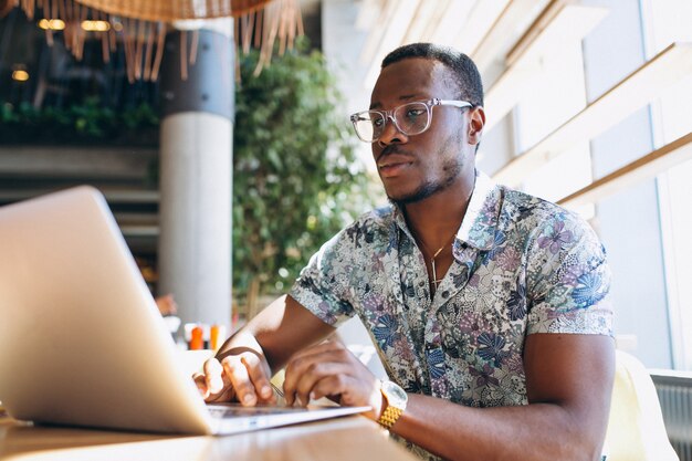 Amerykanina afrykańskiego pochodzenia biznesowy mężczyzna pracuje z laptopem w kawiarni