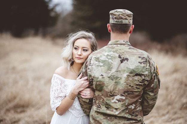 Amerykański żołnierz z kochającą żoną stojącą na suchym trawiastym polu