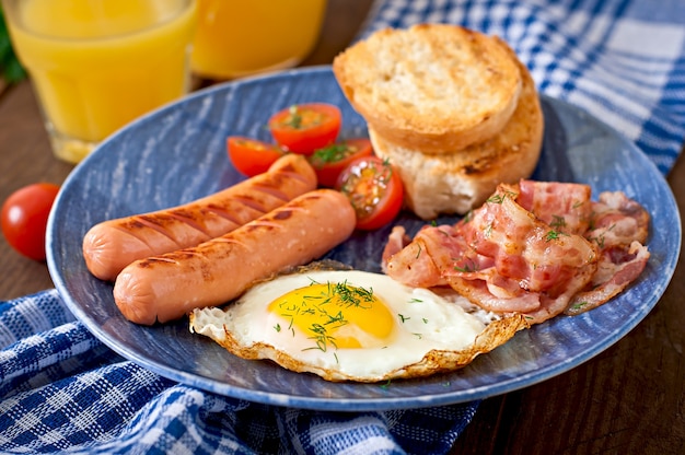 Angielskie śniadanie - tosty, jajko, bekon i warzywa w stylu rustykalnym na drewnianym stole
