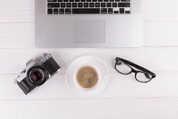 Bezpłatne zdjęcie aparat fotograficzny, okulary, kubek i laptop