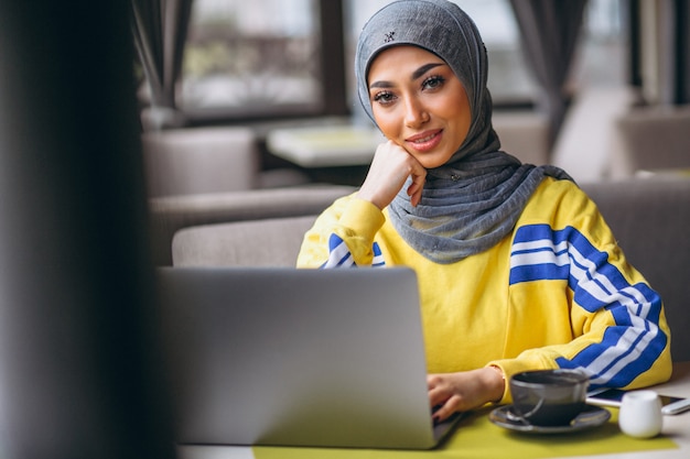 Bezpłatne zdjęcie arabska kobieta w hidżabu wewnątrz kawiarni pracuje na laptopie