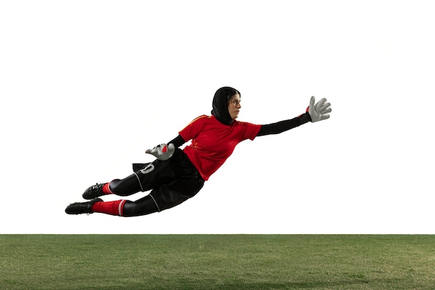 Arabska piłkarz lub piłkarz, bramkarz na tle białego studia. Młoda kobieta łapie piłkę, szkolenie, ochrona celów w ruchu i akcji. Pojęcie sportu, hobby, zdrowego stylu życia.