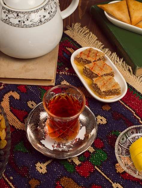 Bezpłatne zdjęcie armudu tradycyjna szklanka herbaty ze słodyczami i sheki pakhlavasi w ciemności