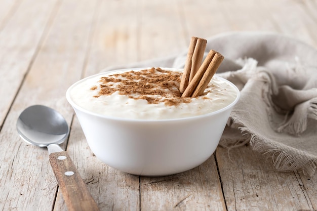 Bezpłatne zdjęcie arroz con leche pudding ryżowy z cynamonem w glinianej misce na drewnianym stole