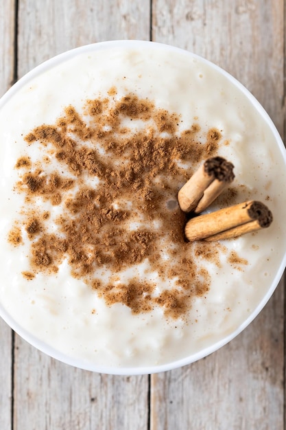 Bezpłatne zdjęcie arroz con leche pudding ryżowy z cynamonem w misce na drewnianym stole