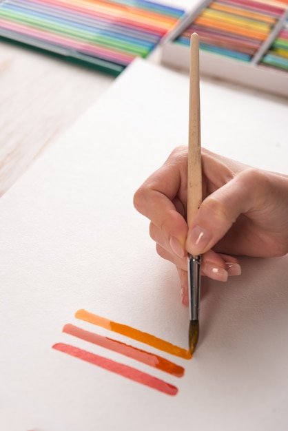 Artysta malujący kolorowe paski pędzlem na białym papierze