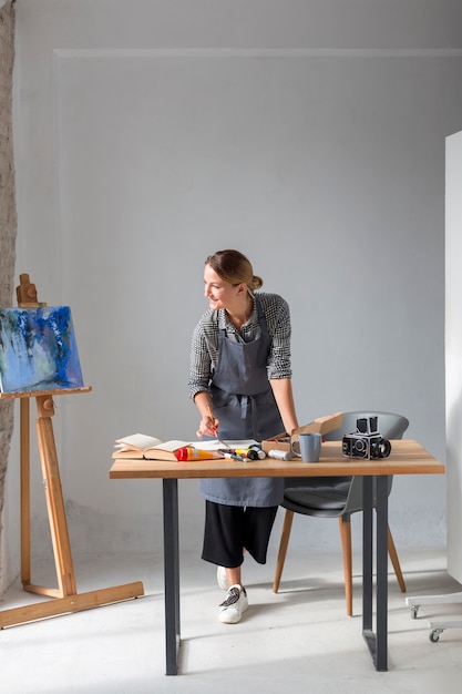 Bezpłatne zdjęcie artysta w fartuchu pracuje na biurku
