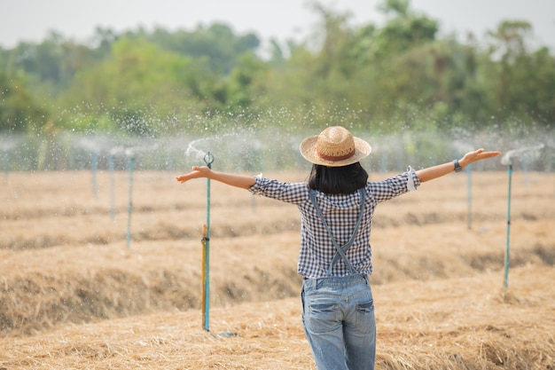 Asia młoda kobieta rolnik w kapeluszu stojący i chodzić w polu kobieta do kontroli w ogrodzie rolniczym. Wzrost rośliny. Pojęcie ekologia, transport, czyste powietrze, żywność, produkt biologiczny.