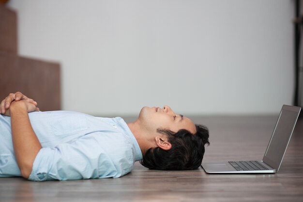 Asian człowiek leżący na podłodze w swoim laptopie