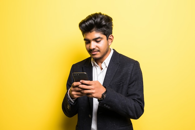 Asianindian biznesowego mężczyzna przystojny mężczyzna używa mądrze telefon na kolor żółty ścianie