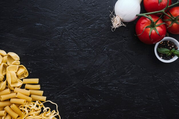 Assorted pasta near vegetables and spices