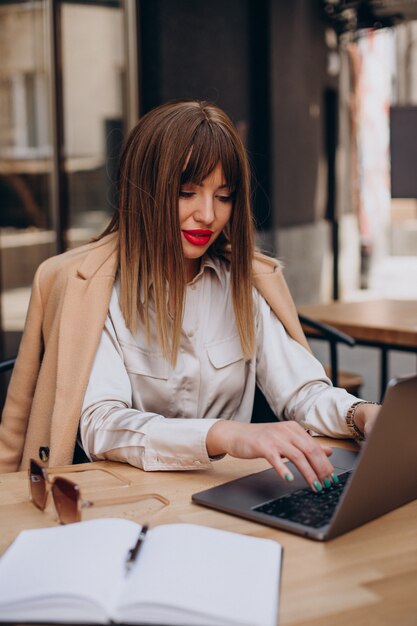 Atrakcyjna biznesowa kobieta pracuje na komputerze w kawiarni
