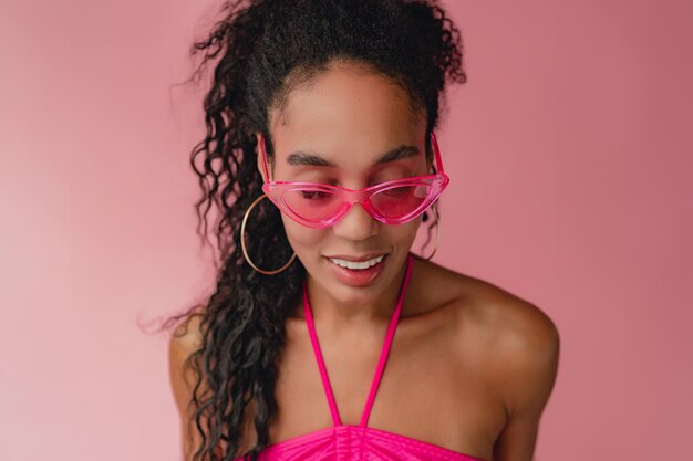 Atrakcyjna czarna afroamerykanka w stylowym stroju na różowym tle